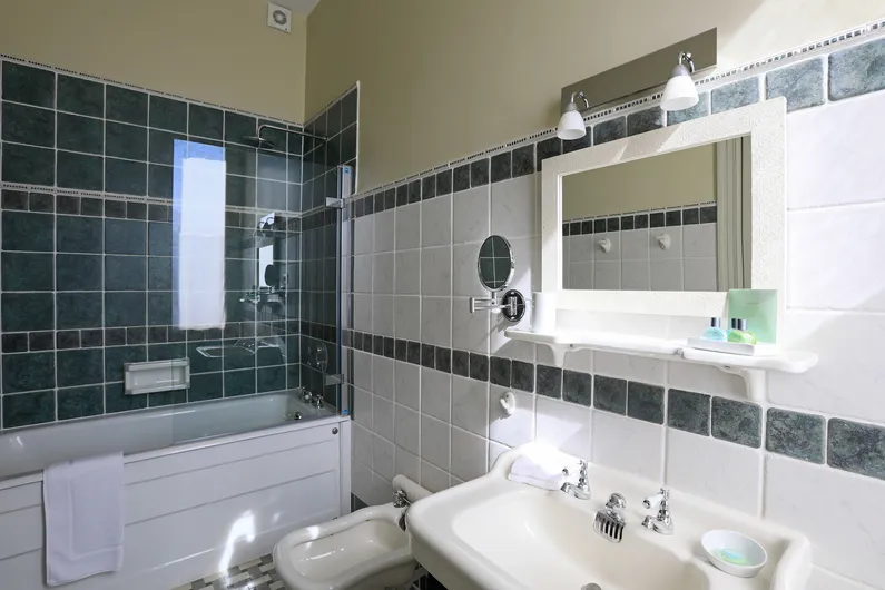 Tiled bathroom with a glass shower screen, sink, and framed mirror