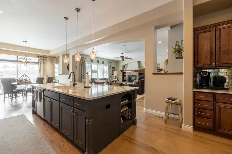 Sunlit kitchen with a large island opening into a living area